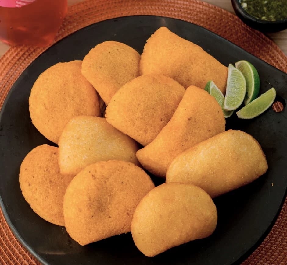 Empanadas doradas de carne, pollo y queso servidas con limón
